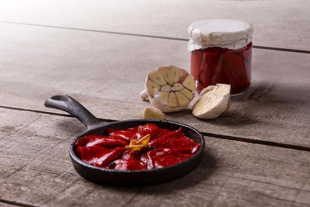 sartén con pimientos, bote en conserva de pimientos y cabeza de ajos